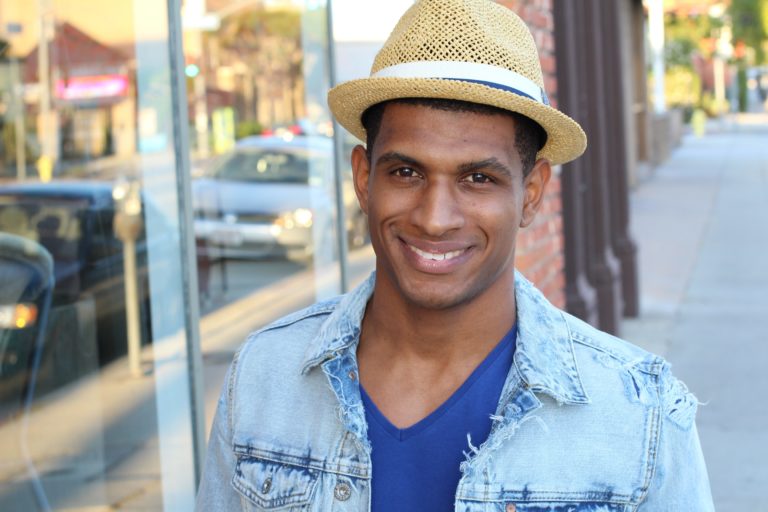 A handsome young man in hipster style clothes wearing a hat