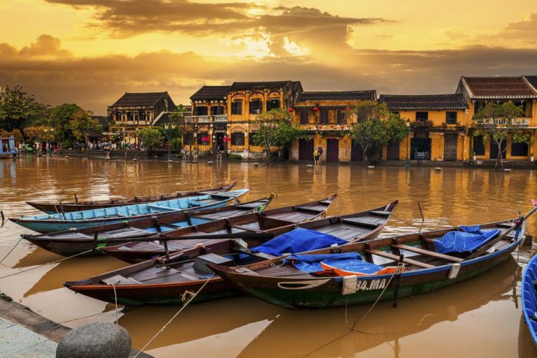 Traditional boats in front of ancient architecture in Hoi An, Vietnam.