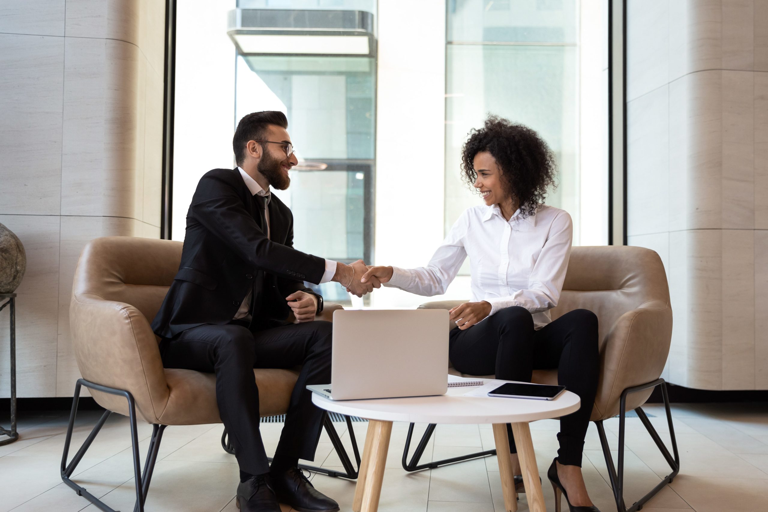Smiling diverse business partners shaking hands at meeting
