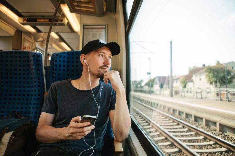 A young man listens to a music or podcast while traveling in a train