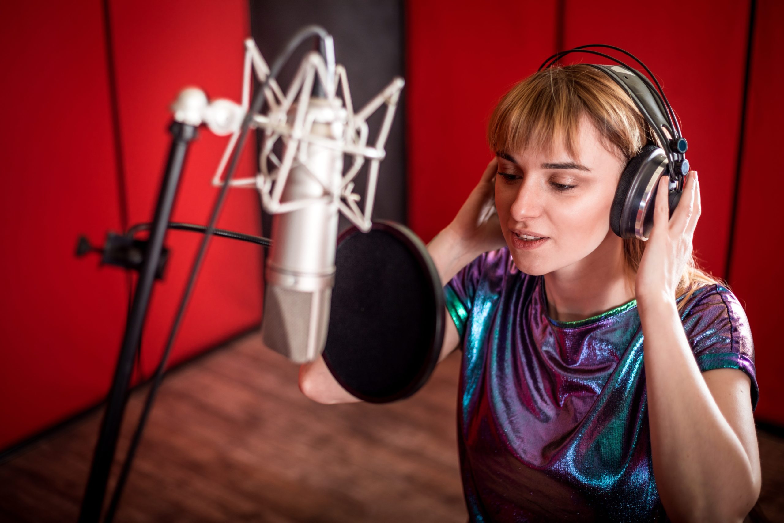 Pretty female singer recording voice in sound studio