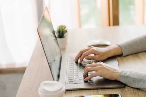 Business woman hand typing laptop computer on wooden table