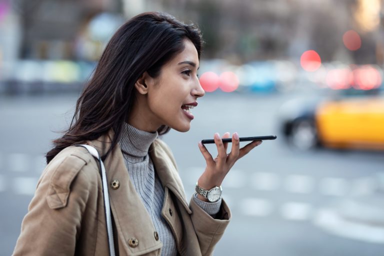 Pretty young woman using voice recognition system on her smartph